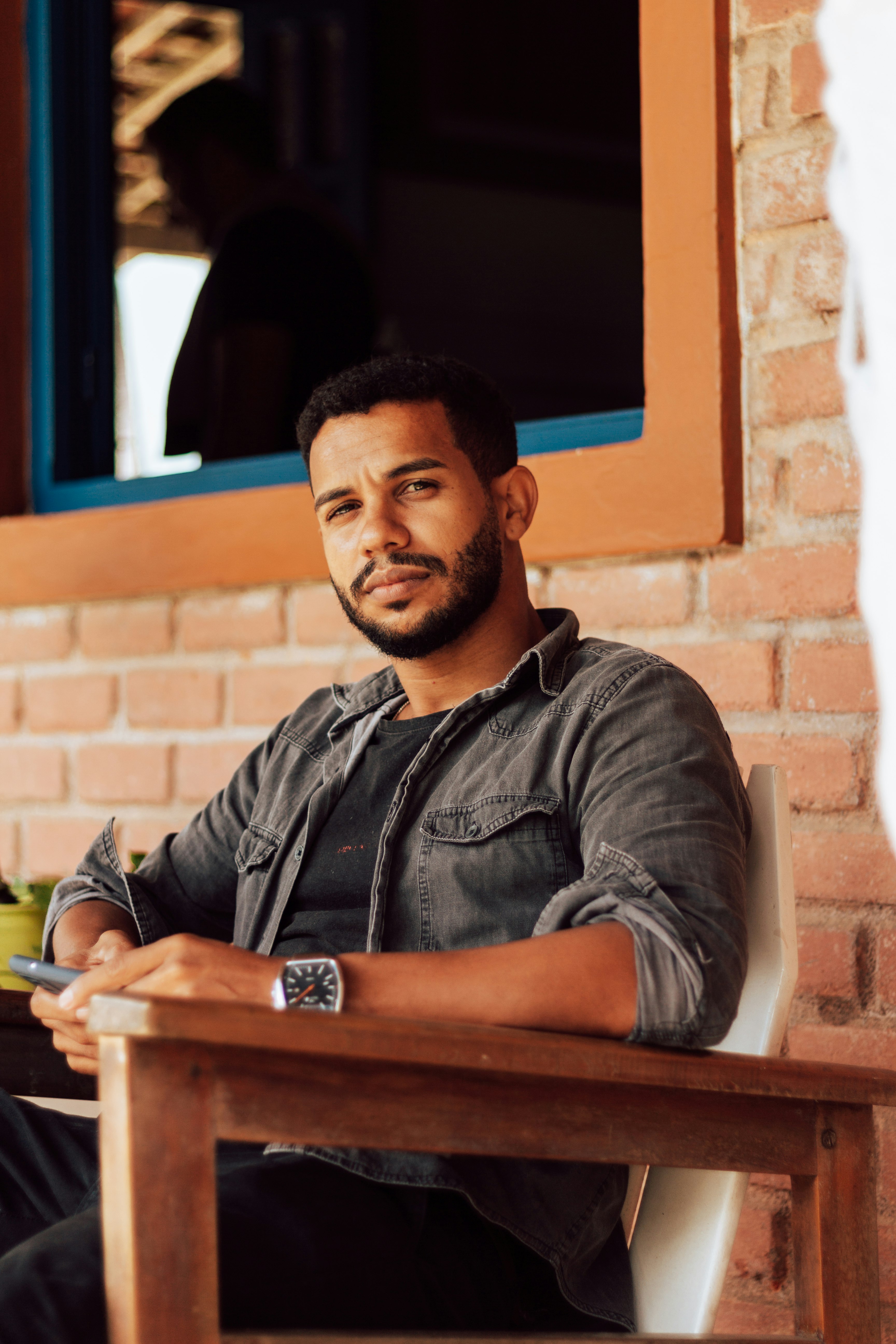 man in black button up shirt sitting on brown wooden bench